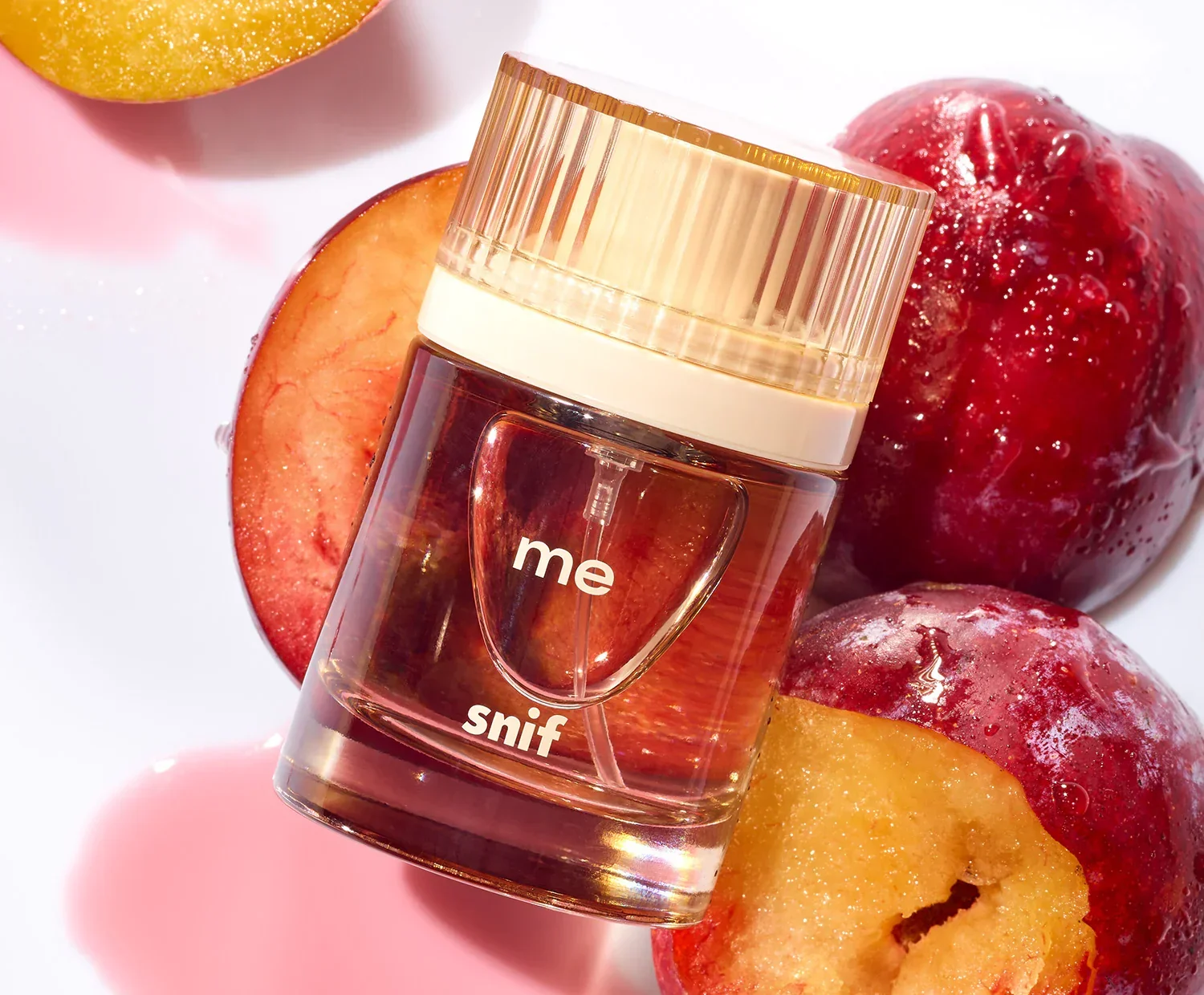 The me fragrance bottle and its mini beside red plums