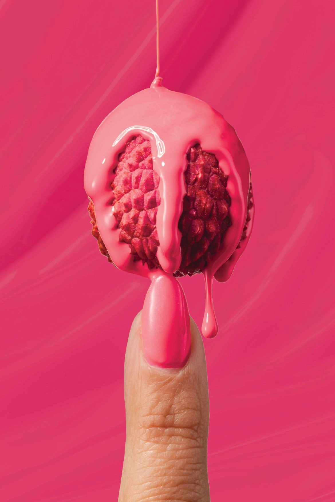 A fingertip holding a glazed fruit dripping pink on a hot-pink backdrop