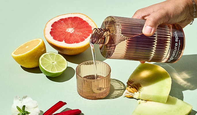 A hand pouring fragrance beside citrus