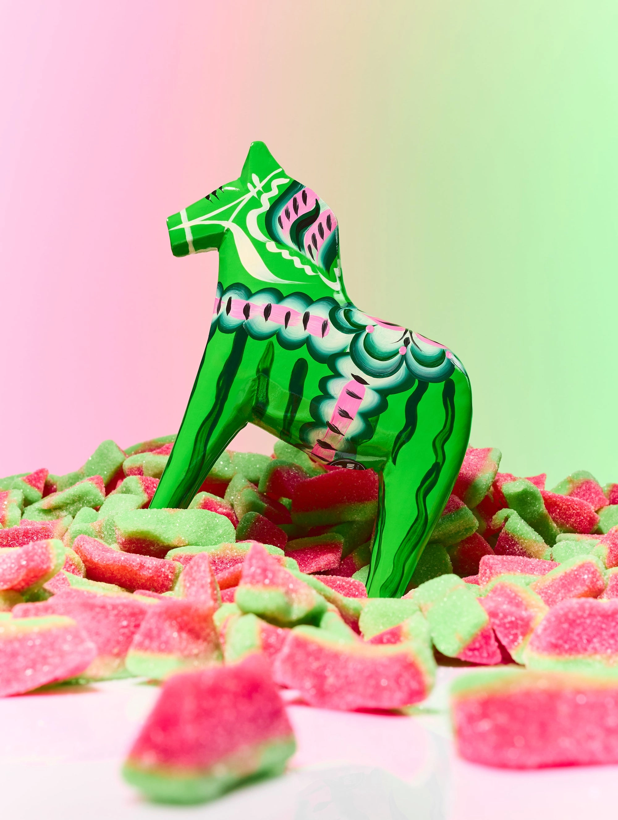 A green watermelon-candy wooden horse on a pink and green backdrop